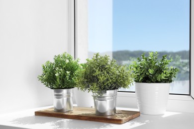 Photo of Artificial potted herbs on sunny day on windowsill indoors. Home decor