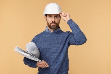 Photo of Architect in hard hat with draft and folder on beige background