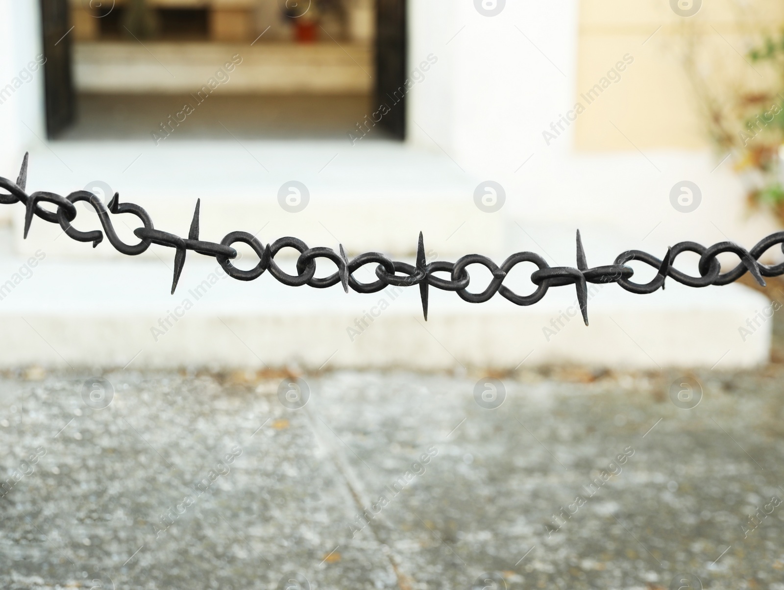 Photo of Beautiful black chain with spikes near building outdoors