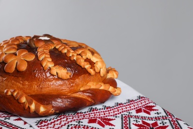 Photo of Rushnyk with korovai on grey background, space for text. Ukrainian bread and salt welcoming tradition