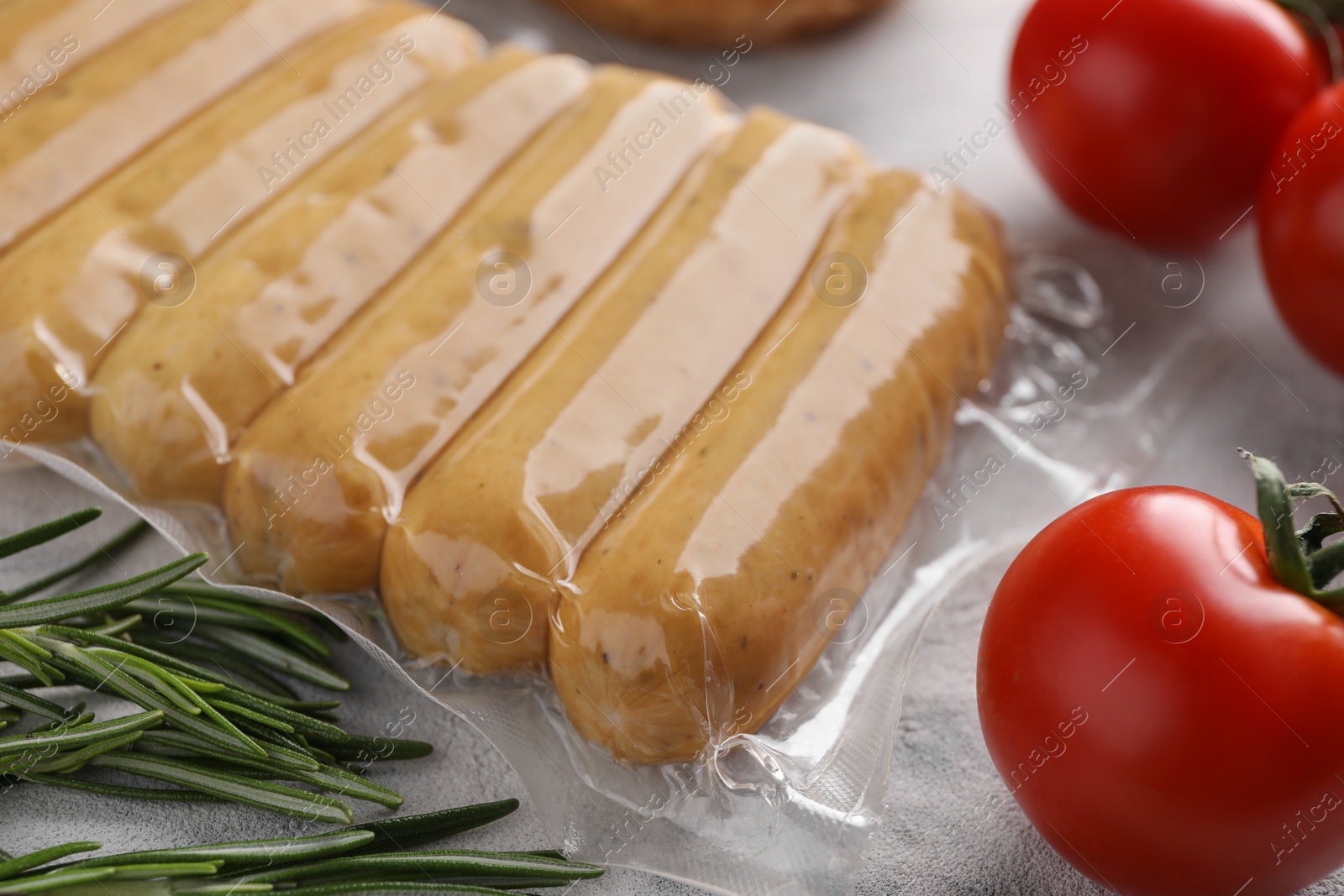 Photo of Vegan sausages, tomatoes and rosemary on white table, closeup