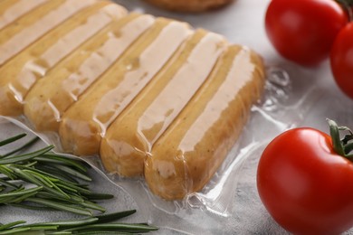 Photo of Vegan sausages, tomatoes and rosemary on white table, closeup