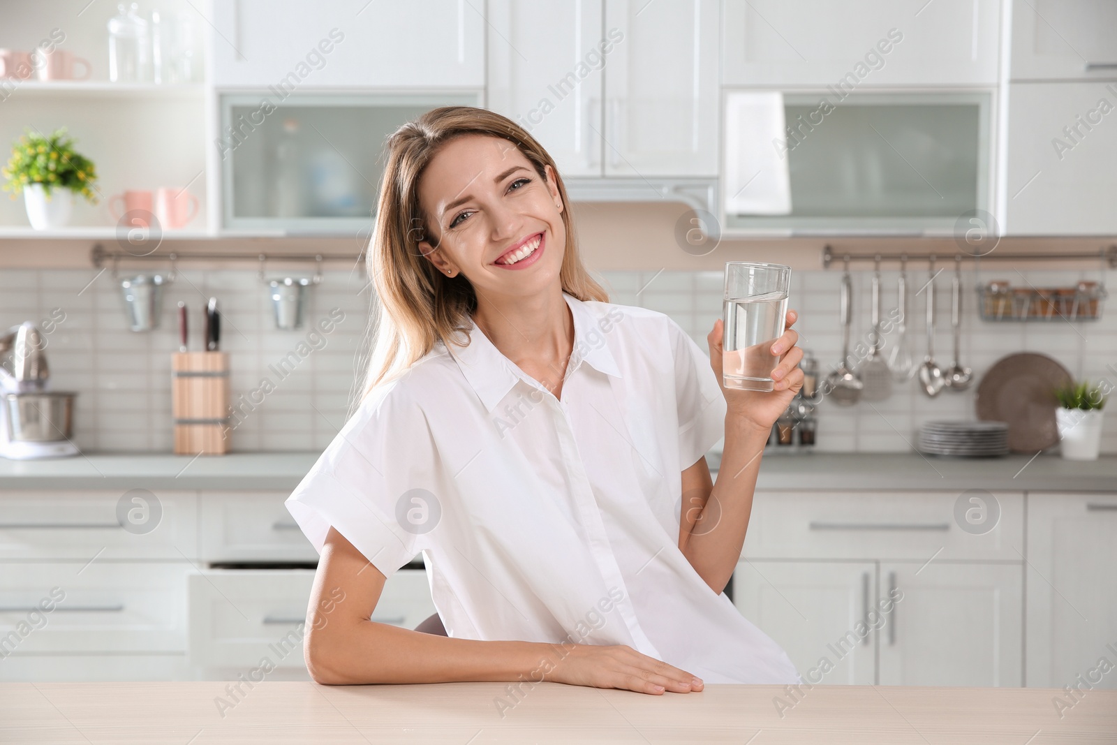 Photo of Young woman holding glass with clean water in kitchen