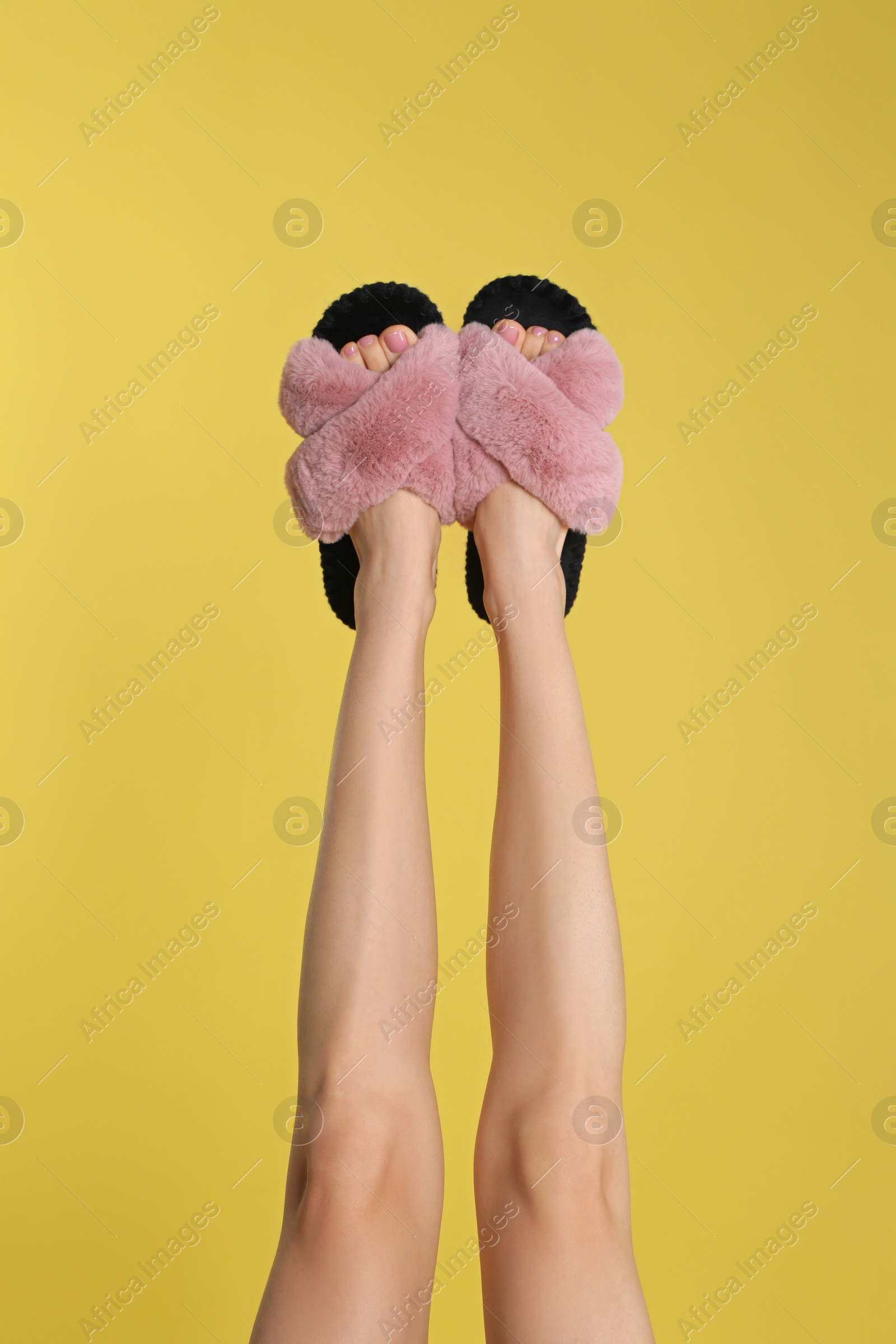 Photo of Woman wearing stylish slippers on yellow background, closeup