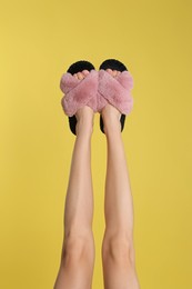 Woman wearing stylish slippers on yellow background, closeup