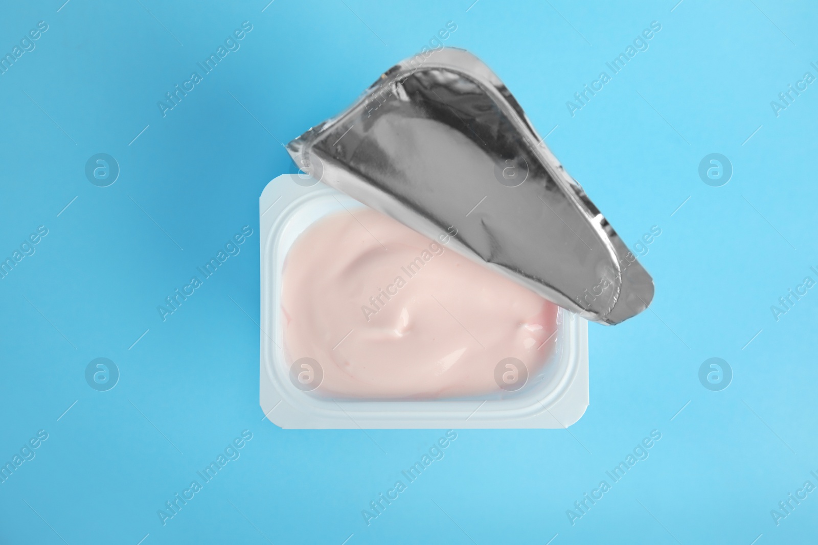 Photo of Tasty organic yogurt on light blue background, top view