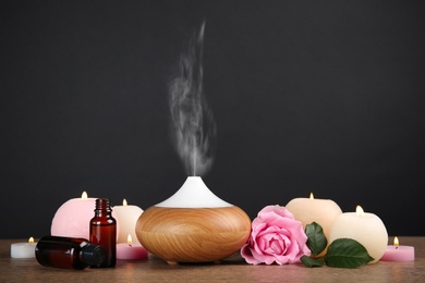 Composition with essential oils diffuser on table against black background. Space for text