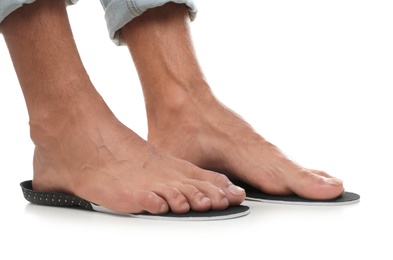 Man fitting orthopedic insoles on white background, closeup. Foot care