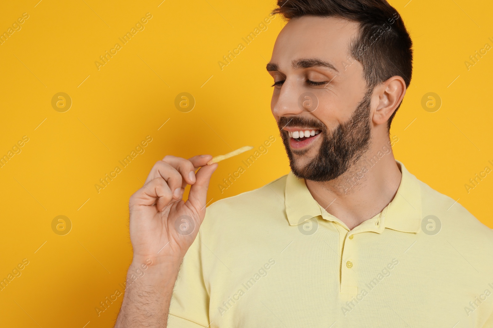 Photo of Man with French fries on yellow background, space for text