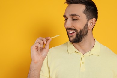 Man with French fries on yellow background, space for text