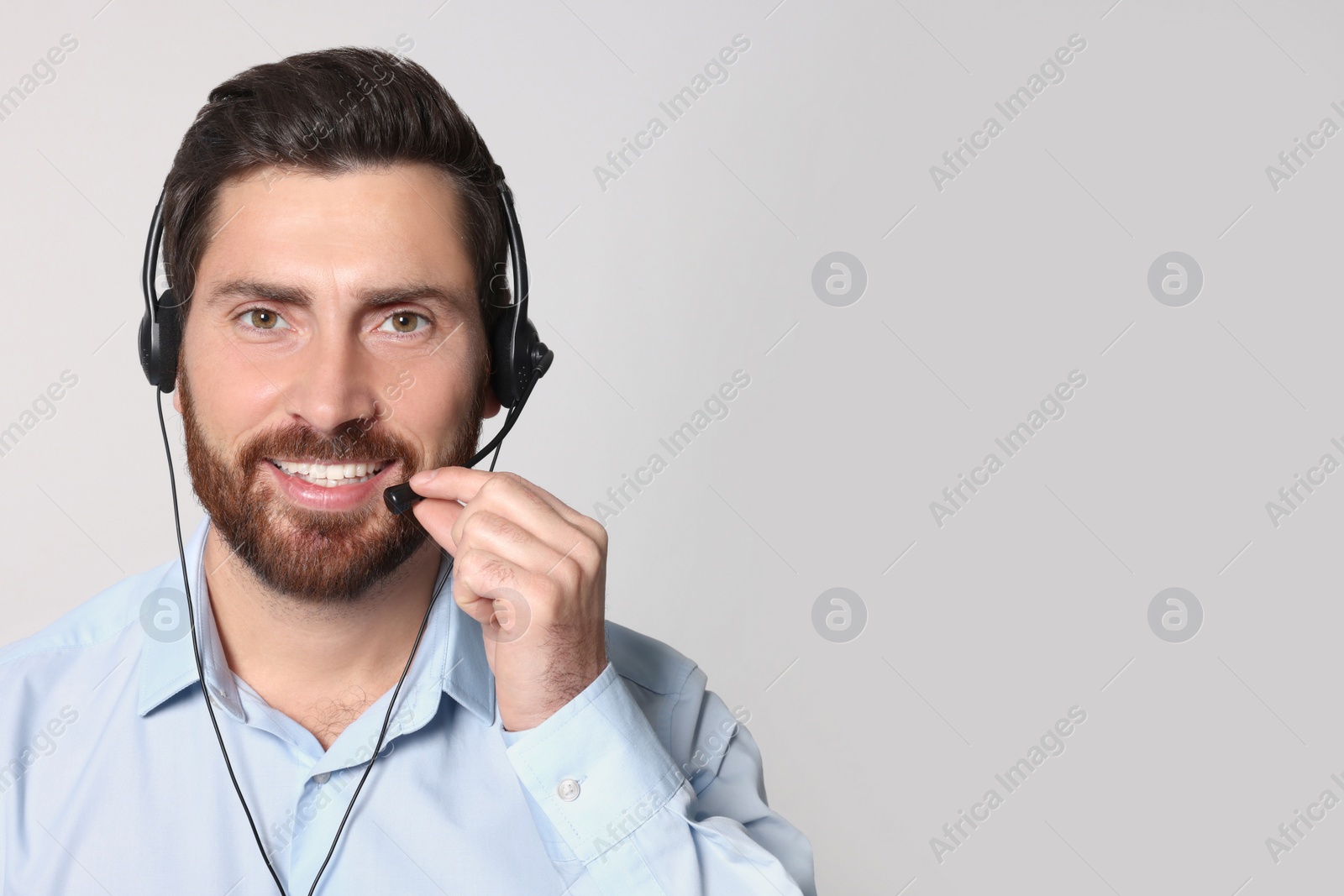 Photo of Hotline operator with headset on light grey background, space for text