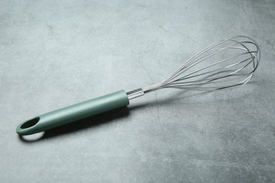 Photo of Metal whisk on gray table. Kitchen tool