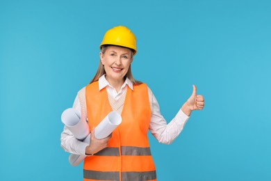 Architect in hard hat with drafts showing thumbs up on light blue background