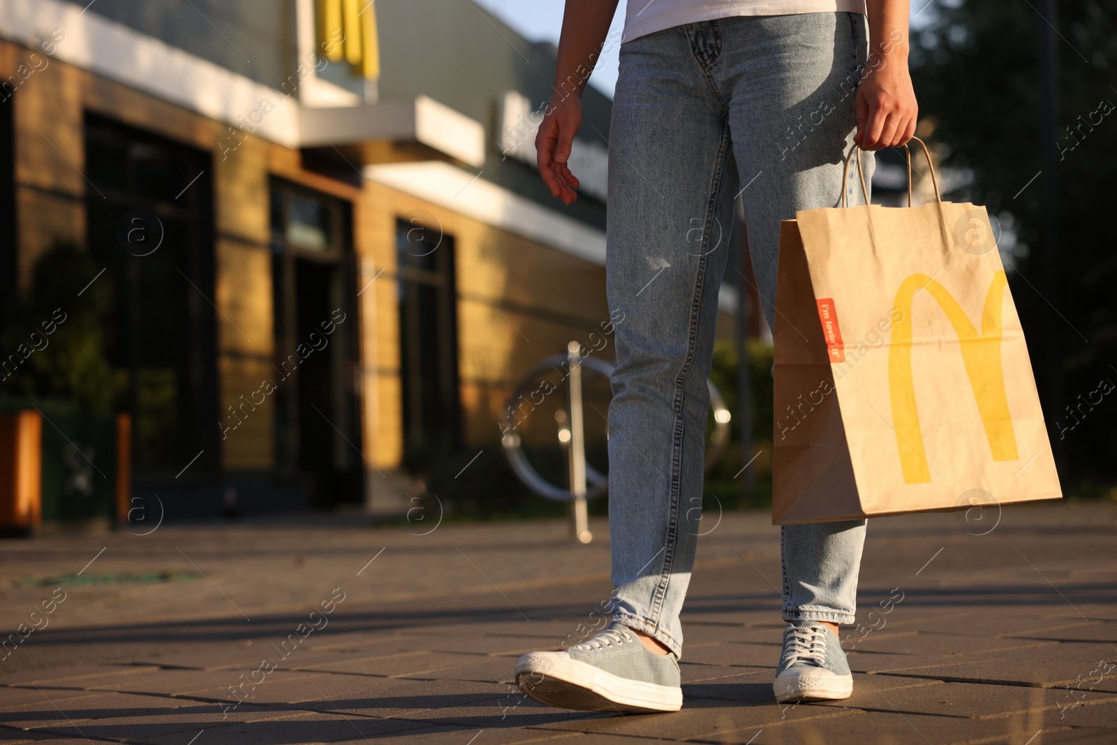 Photo of Lviv, Ukraine - September 26, 2023: Woman with McDonald's paper bag outdoors, closeup. Space for text