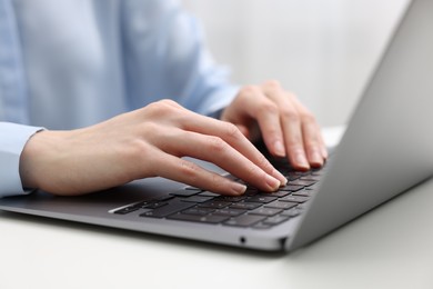 E-learning. Woman using laptop at white table indoors, closeup