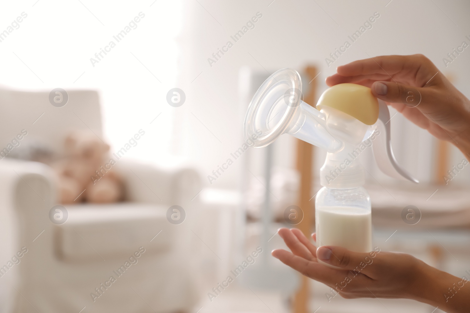 Photo of Closeup view of woman holding manual breast pump indoors, space for text. Baby health