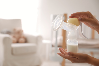 Photo of Closeup view of woman holding manual breast pump indoors, space for text. Baby health