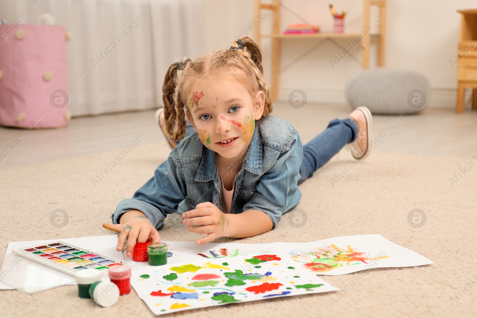 Photo of Cute little child painting on floor at home