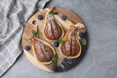 Photo of Delicious pears baked in puff pastry with powdered sugar served on grey table, top view
