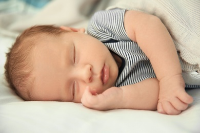 Adorable newborn baby peacefully sleeping on bed