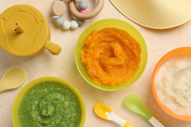 Photo of Baby food. Different tasty puree in bowls served on beige textured table, flat lay