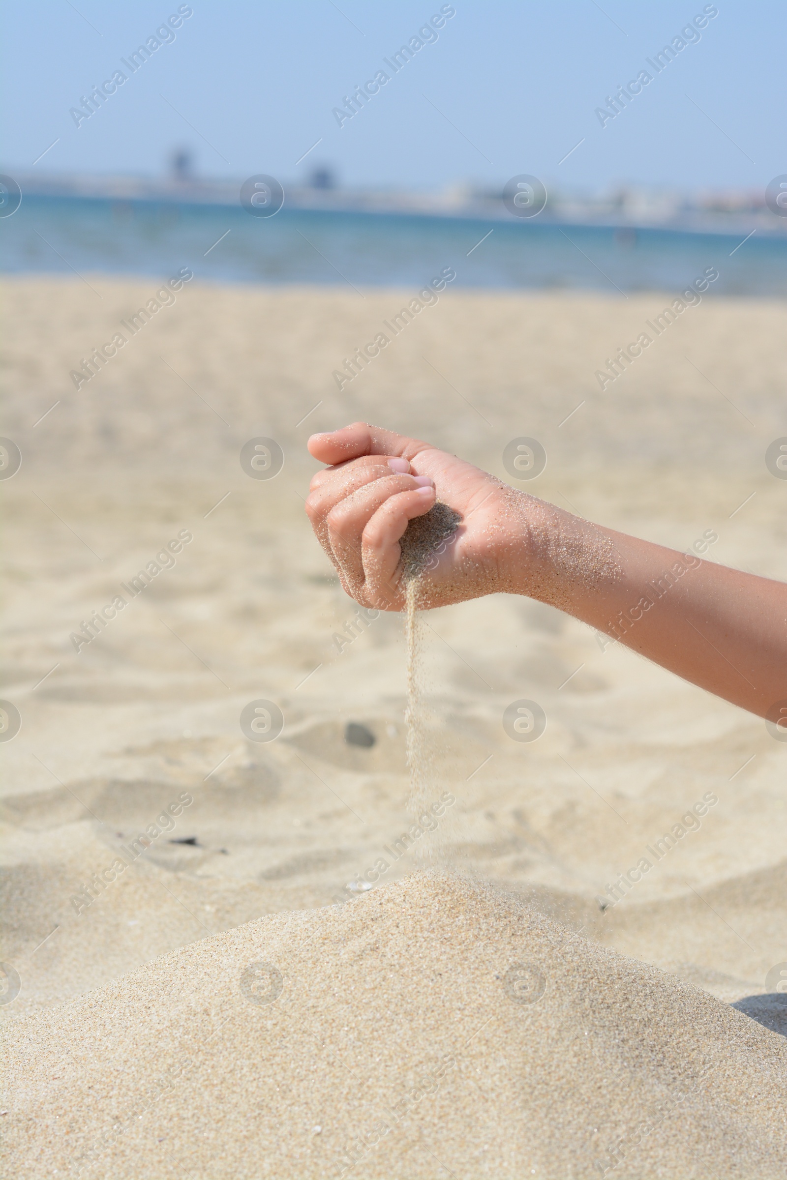 Photo of Child pouring sand from hand on beach, closeup. Fleeting time concept