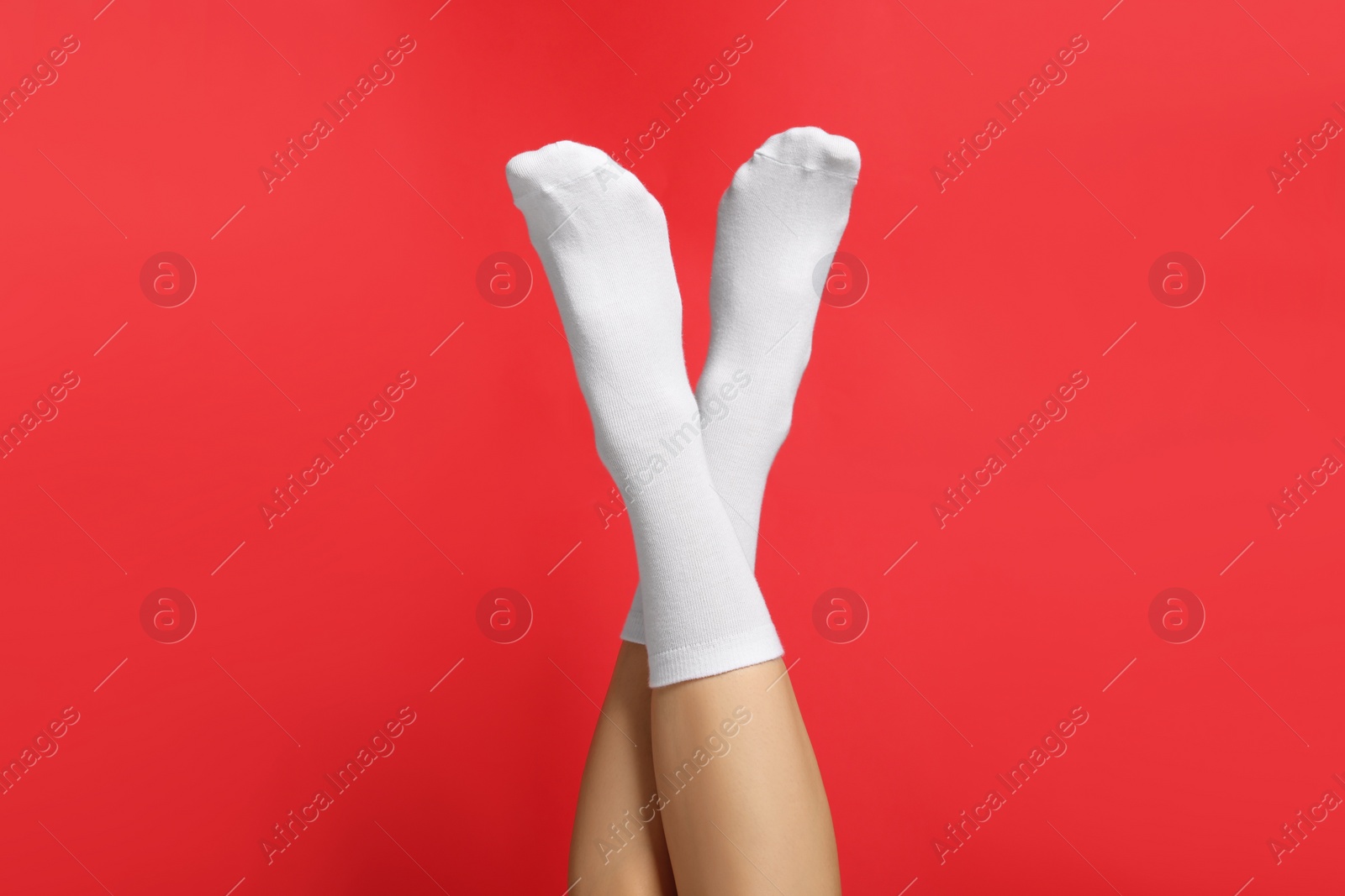 Photo of Woman in stylish white socks on red background, closeup