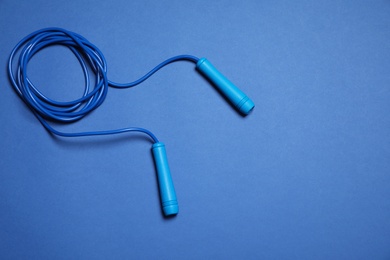 Skipping rope on blue background, top view