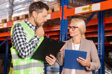 Photo of Manager and worker in warehouse with lots of products