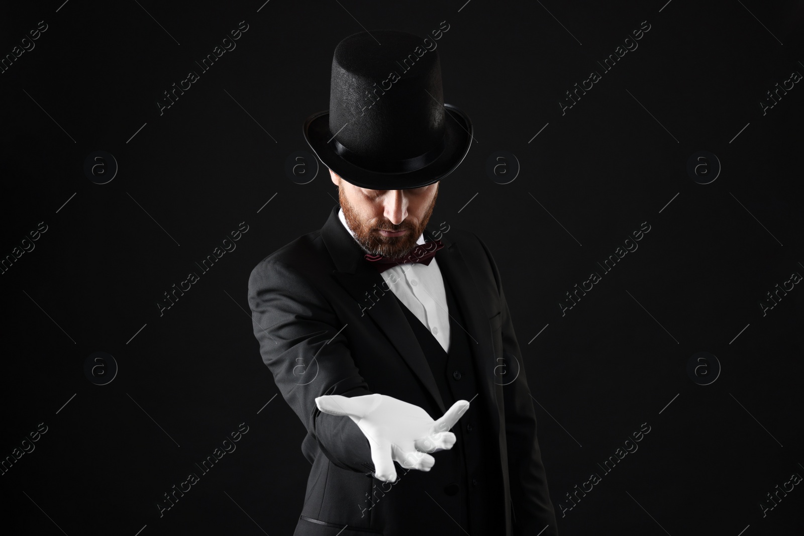 Photo of Magician in top hat on black background