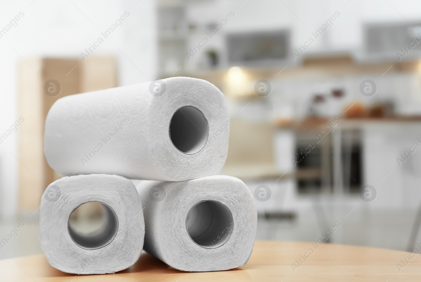 Photo of Rolls of paper towels on table in kitchen, space for text