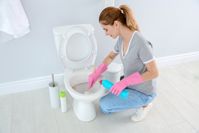 Photo of Woman cleaning toilet bowl in bathroom