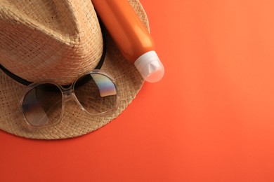 Photo of Bottle of sunscreen and beach accessories on coral background, top view. Space for text