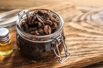 Glass jar of coffee scrub on wooden board