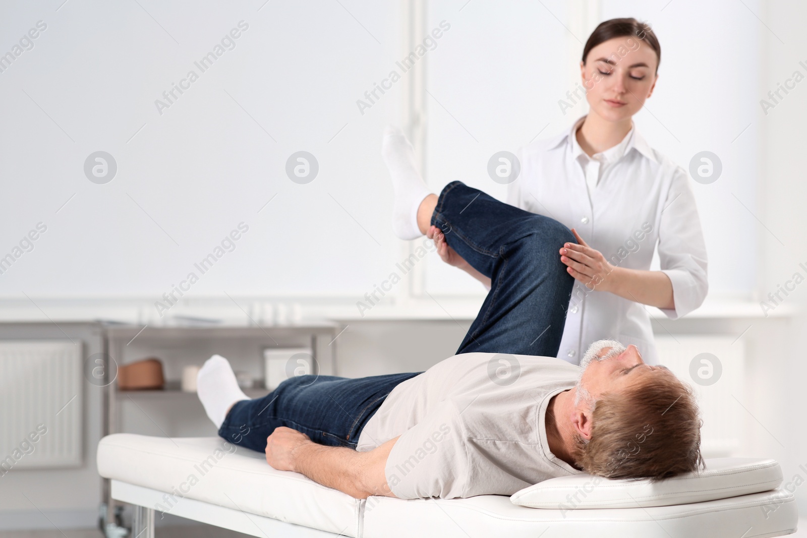 Photo of Professional orthopedist examining patient's leg in clinic