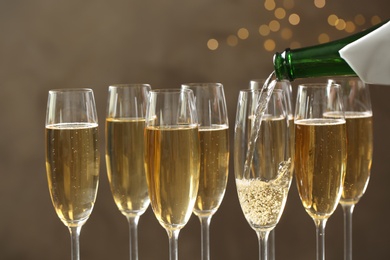 Photo of Pouring champagne into glasses on blurred background, closeup