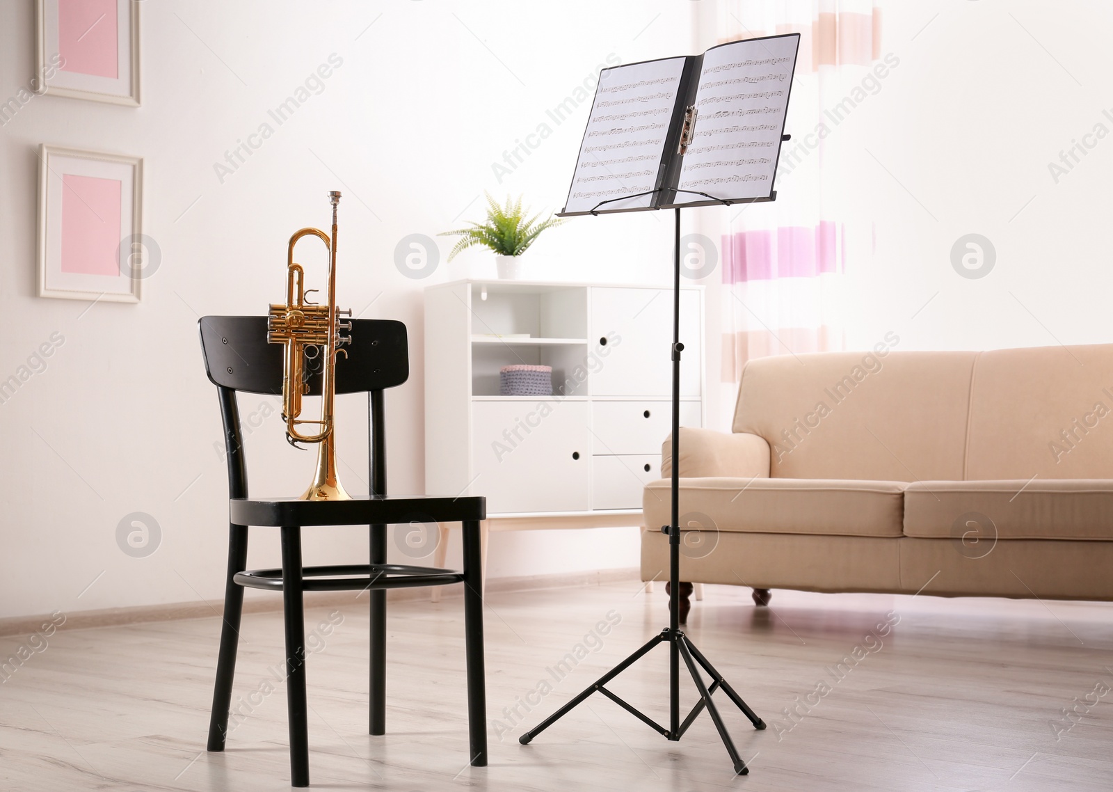 Photo of Trumpet, chair and note stand with music sheets in room