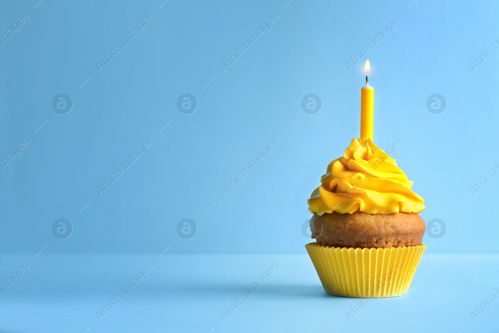 Photo of Delicious birthday cupcake with candle on color background