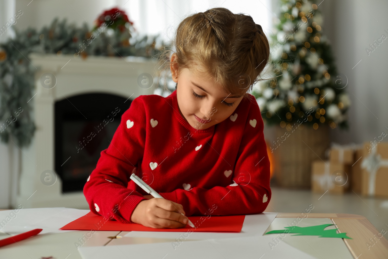 Photo of Cute child writing letter to Santa Claus at table indoors. Christmas tradition