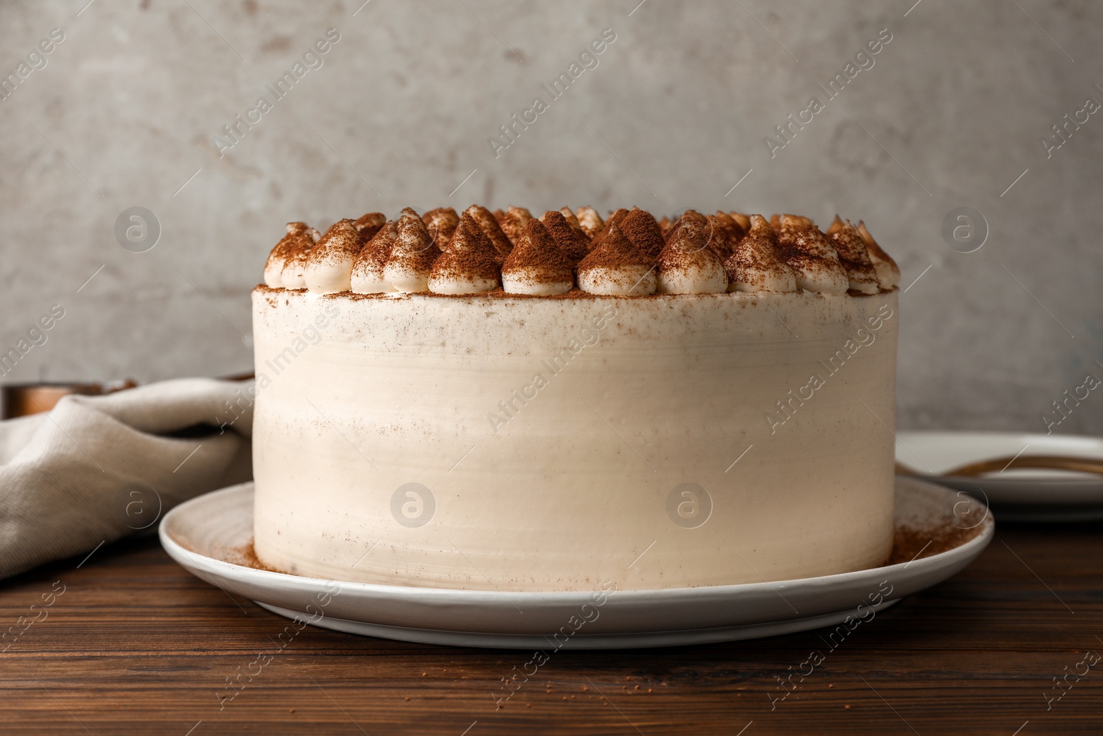 Photo of Delicious tiramisu cake with cocoa powder on wooden table