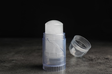 Photo of Natural crystal alum deodorant and cap on grey table against black background