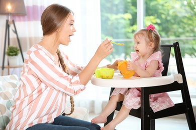 Caring mother feeding her cute little baby with healthy food at home
