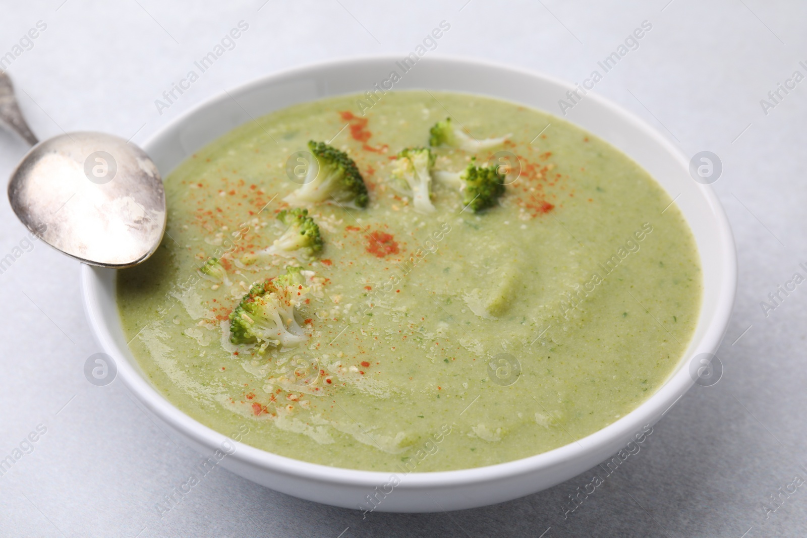 Photo of Delicious broccoli cream soup served on light table, closeup