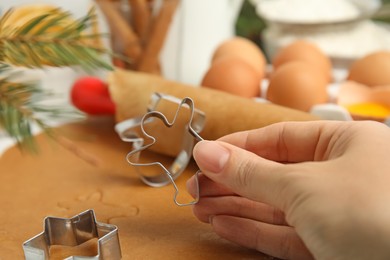 Woman holding cookie cutter at table, closeup. Christmas biscuits