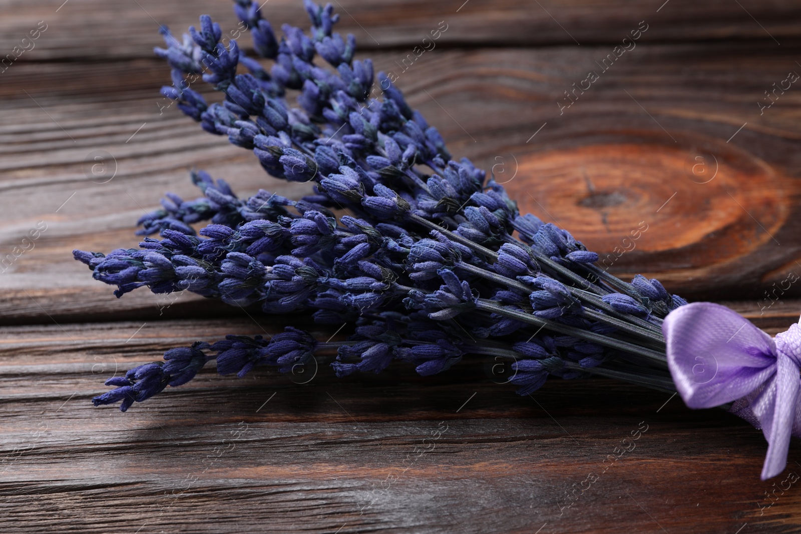 Photo of Bouquet of beautiful preserved lavender flowers on wooden table, closeup