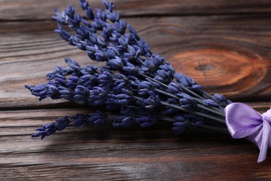 Photo of Bouquet of beautiful preserved lavender flowers on wooden table, closeup