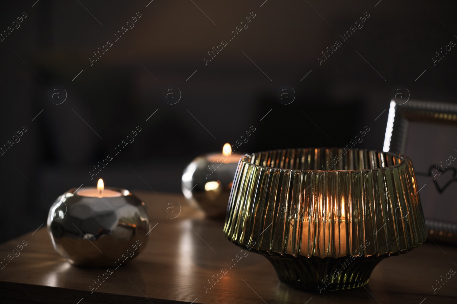 Photo of Stylish lantern with burning candle on wooden table indoors. Space for text