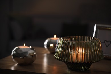 Stylish lantern with burning candle on wooden table indoors. Space for text