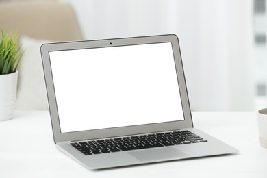 Photo of Laptop with blank screen on table indoors. Space for text