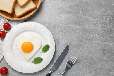 Photo of Heart shaped fried egg served on grey marble table, flat lay. Space for text